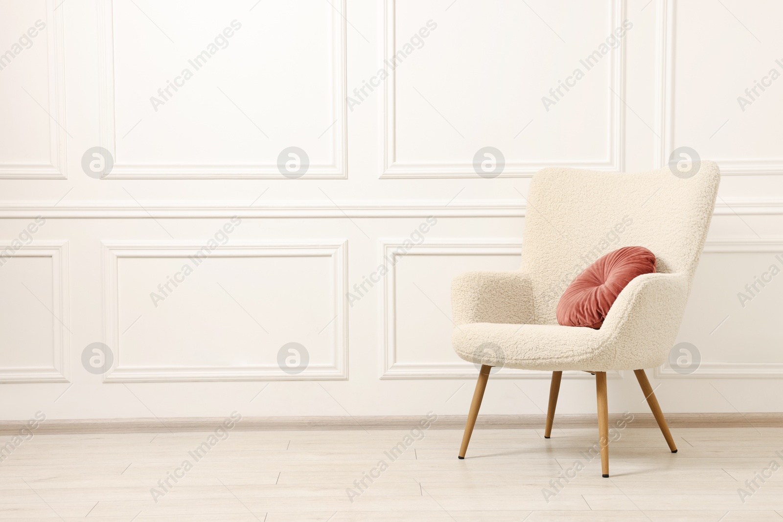 Photo of Soft armchair with pillow in light room. Space for text