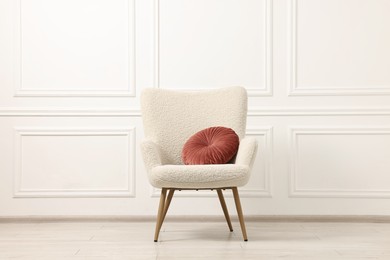 Photo of Soft armchair with pillow in light room