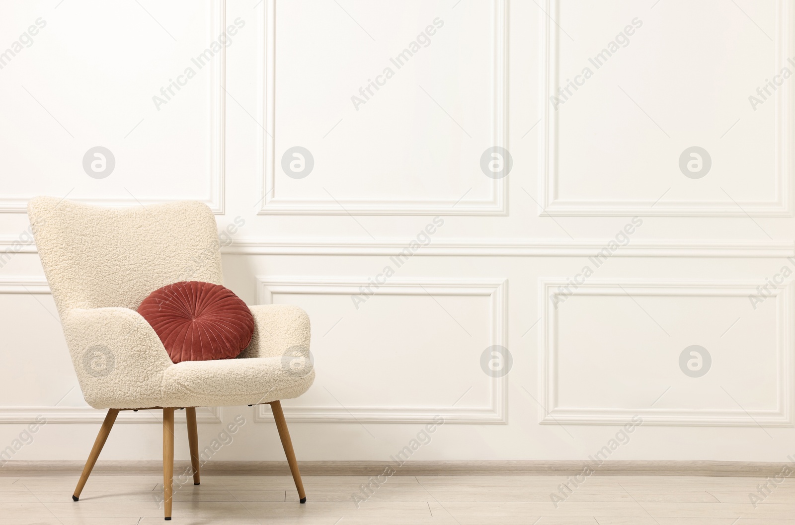 Photo of Soft armchair with pillow in light room. Space for text