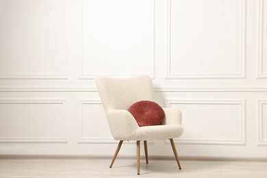 Photo of Soft armchair with pillow in light room