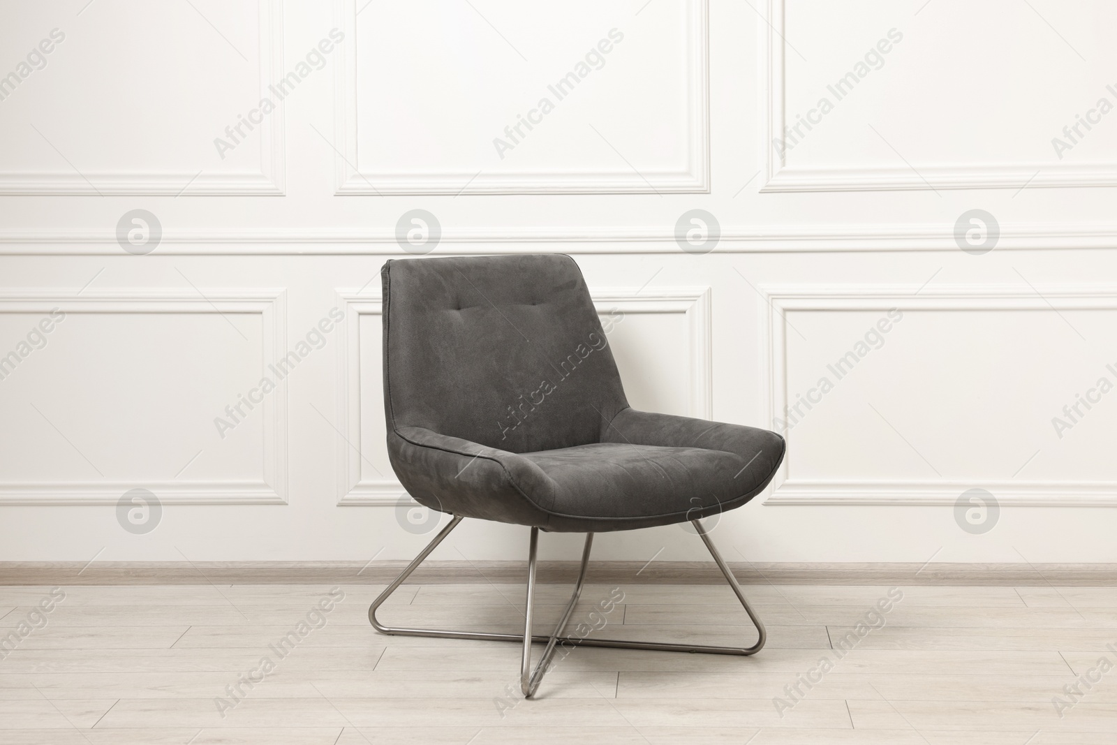 Photo of One soft armchair near white wall indoors