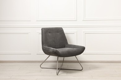 One soft armchair near white wall indoors