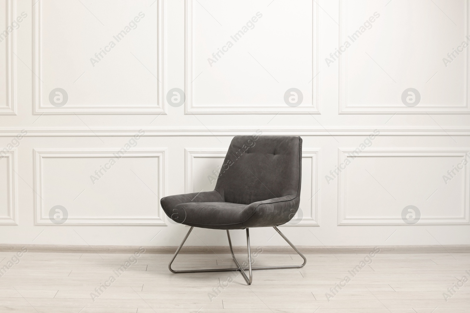 Photo of One soft armchair near white wall indoors