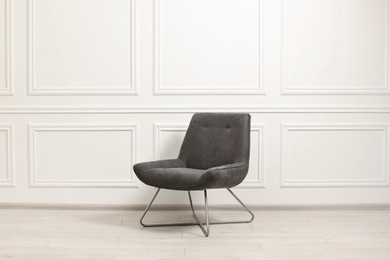 One soft armchair near white wall indoors