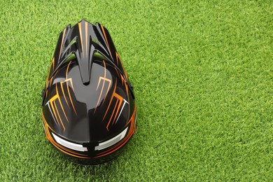 Photo of Modern motorcycle helmet with visor on green grass, above view. Space for text