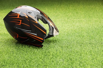 Photo of Modern motorcycle helmet with visor on green grass, space for text