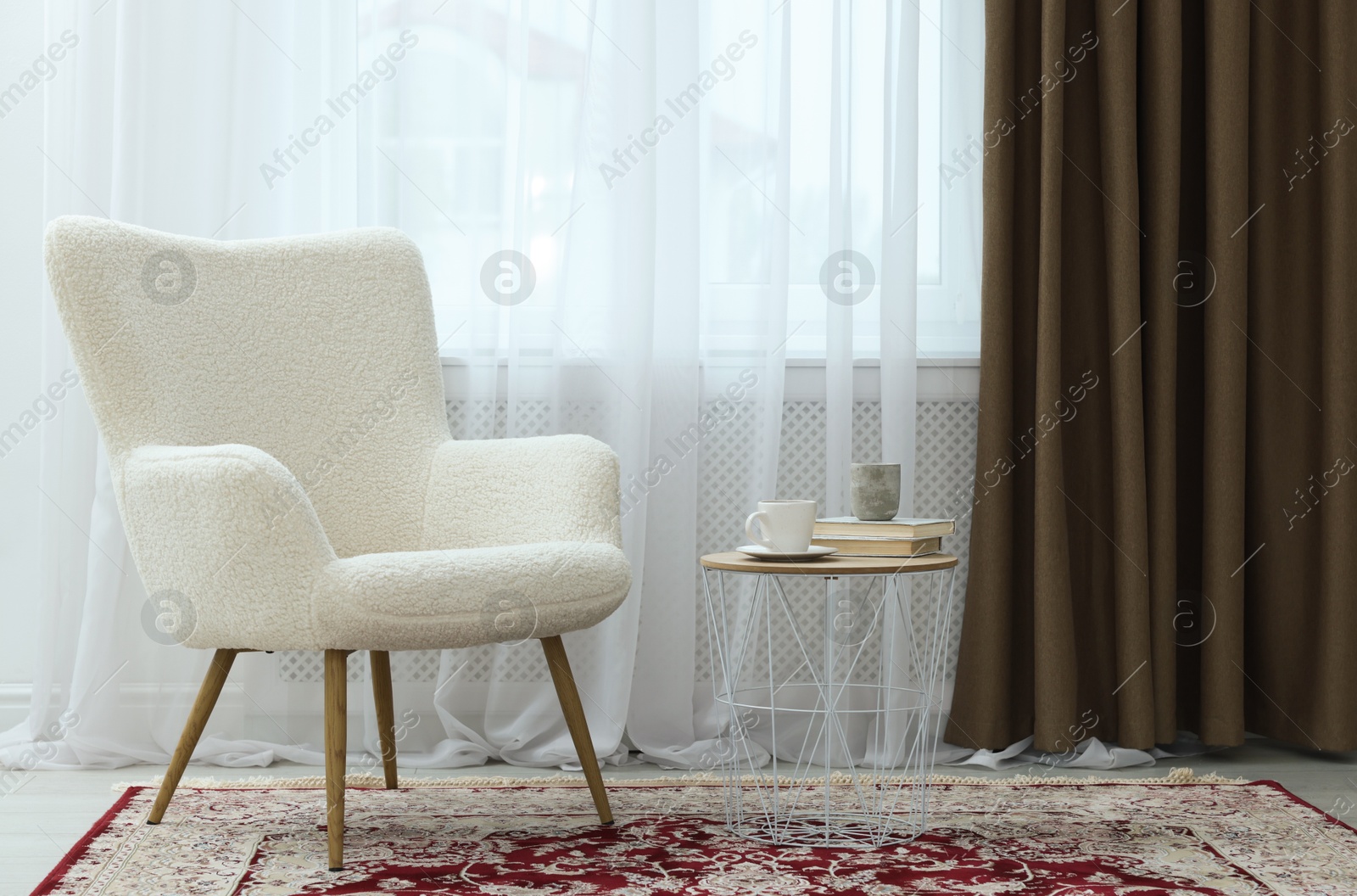 Photo of Soft armchair, side table and window with curtains indoors. Interior design