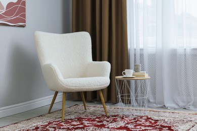 Photo of Soft armchair, side table and window with curtains indoors. Interior design