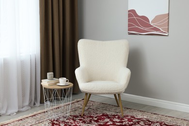 Photo of Soft armchair, side table and window with curtains indoors. Interior design