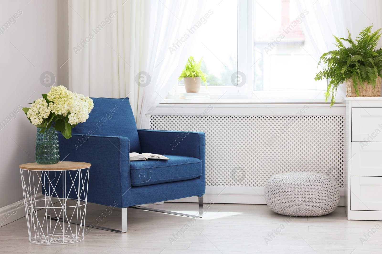 Photo of Soft armchair, side table, flowers and window with curtains in room. Interior design