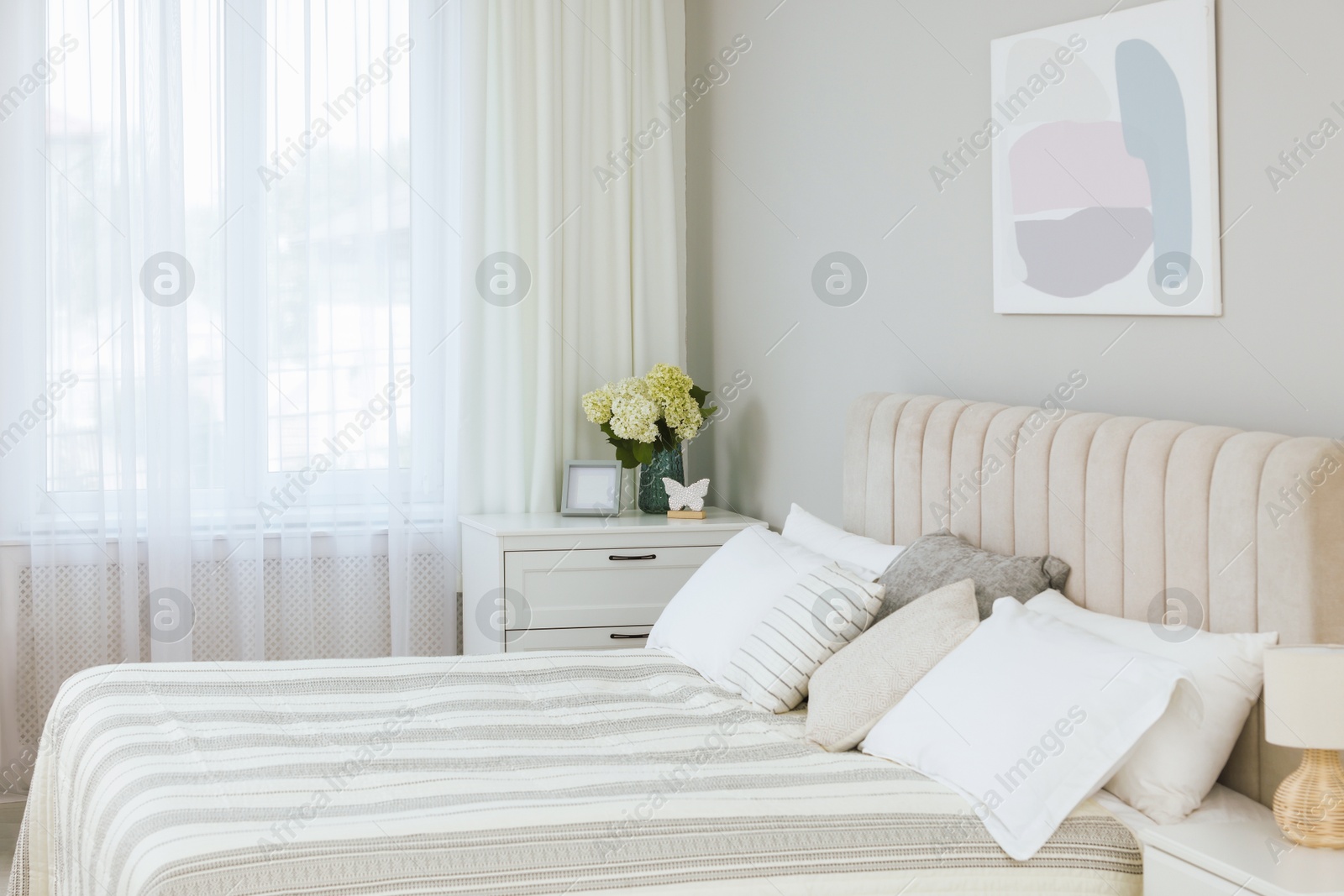 Photo of Large bed, nightstand, chest of drawers and window with curtains in bedroom. Interior design