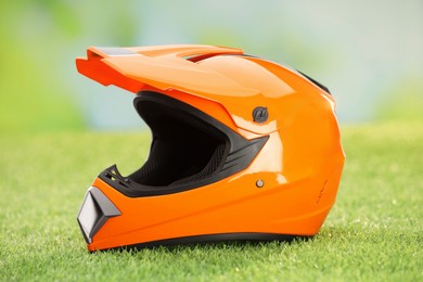 Orange motorcycle helmet with visor on green grass