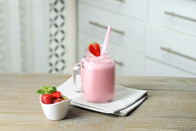 Photo of Tasty yogurt in mason jar and fresh strawberries on wooden table