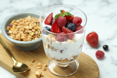 Photo of Tasty yogurt with fresh berries and granola served on white marble table, closeup