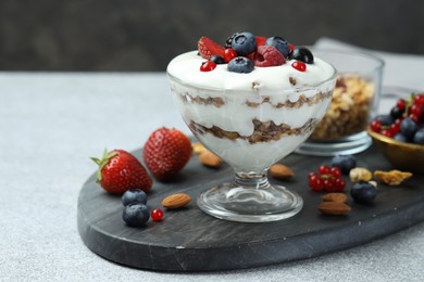 Tasty yogurt with fresh berries, granola and nuts on gray table, closeup