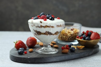 Tasty yogurt with fresh berries, granola and nuts on gray table