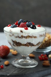 Tasty yogurt with fresh berries, granola and nuts on table