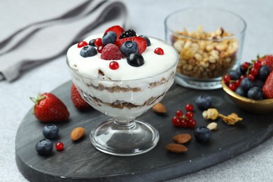 Photo of Tasty yogurt with fresh berries, granola and nuts on gray table, closeup
