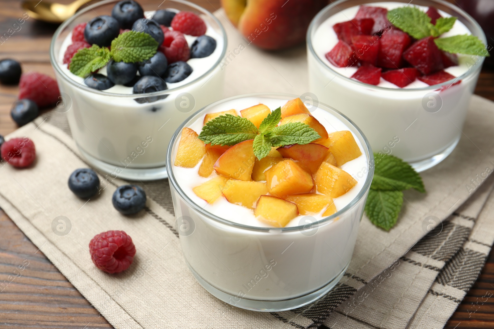 Photo of Tasty yogurt with fresh berries, fruits and mint in glasses on wooden table, closeup