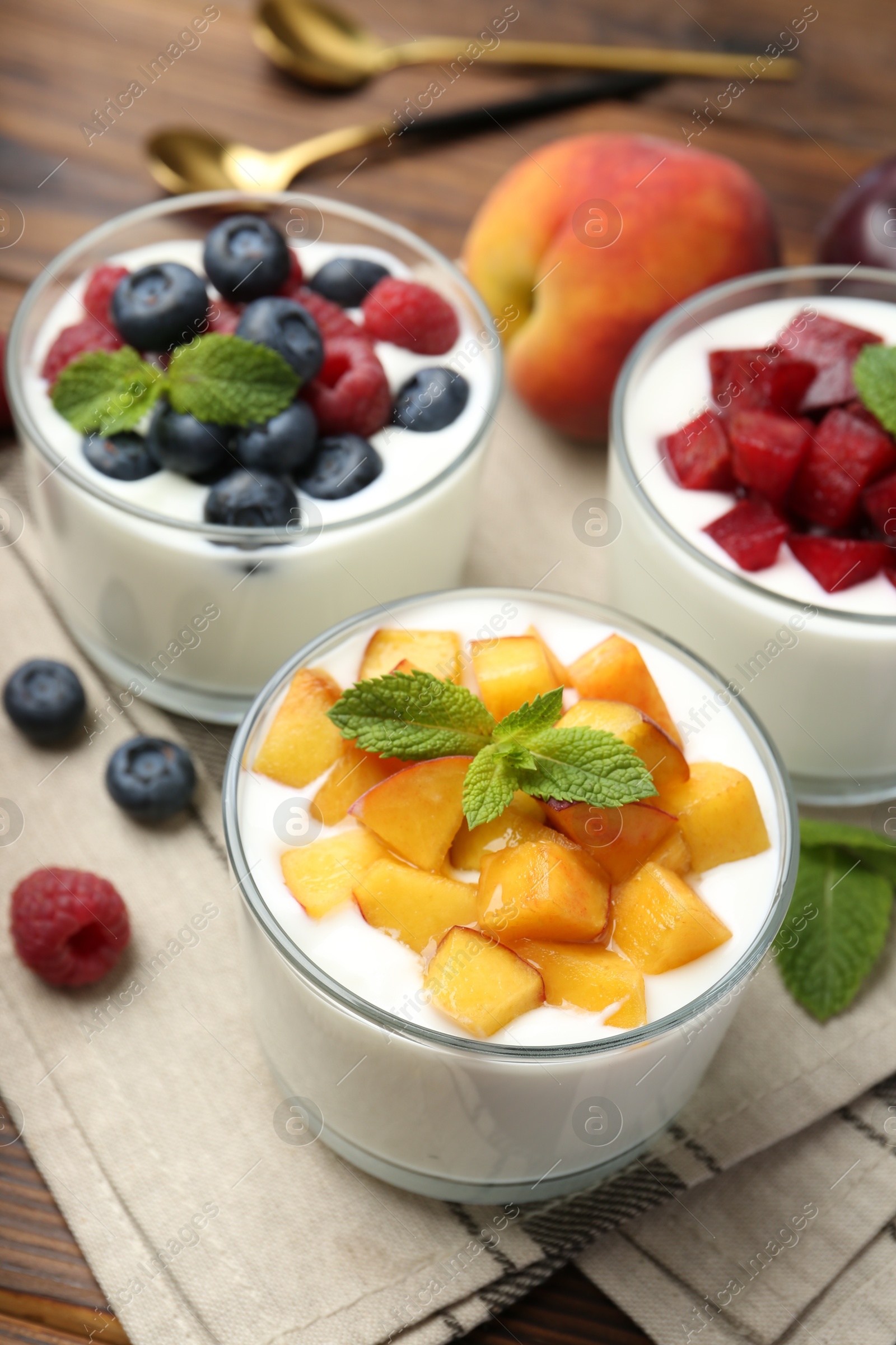 Photo of Tasty yogurt with fresh berries, fruits and mint in glasses on table, closeup