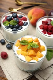 Photo of Tasty yogurt with fresh berries, fruits and mint in glasses on table, closeup