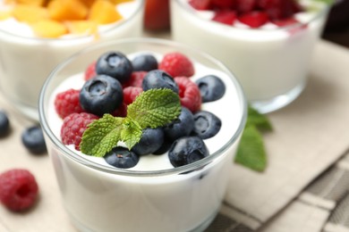 Photo of Tasty yogurt with fresh berries, fruits and mint in glasses on table, closeup