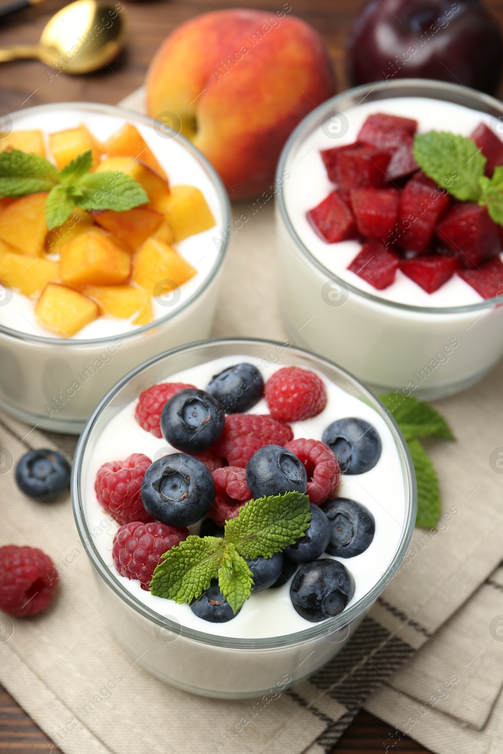 Photo of Tasty yogurt with fresh berries, fruits and mint in glasses on table, closeup