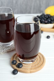 Tasty fresh acai juice in glasses with berries on white wooden table, closeup