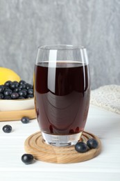 Photo of Tasty fresh acai juice in glass with berries on white wooden table, closeup