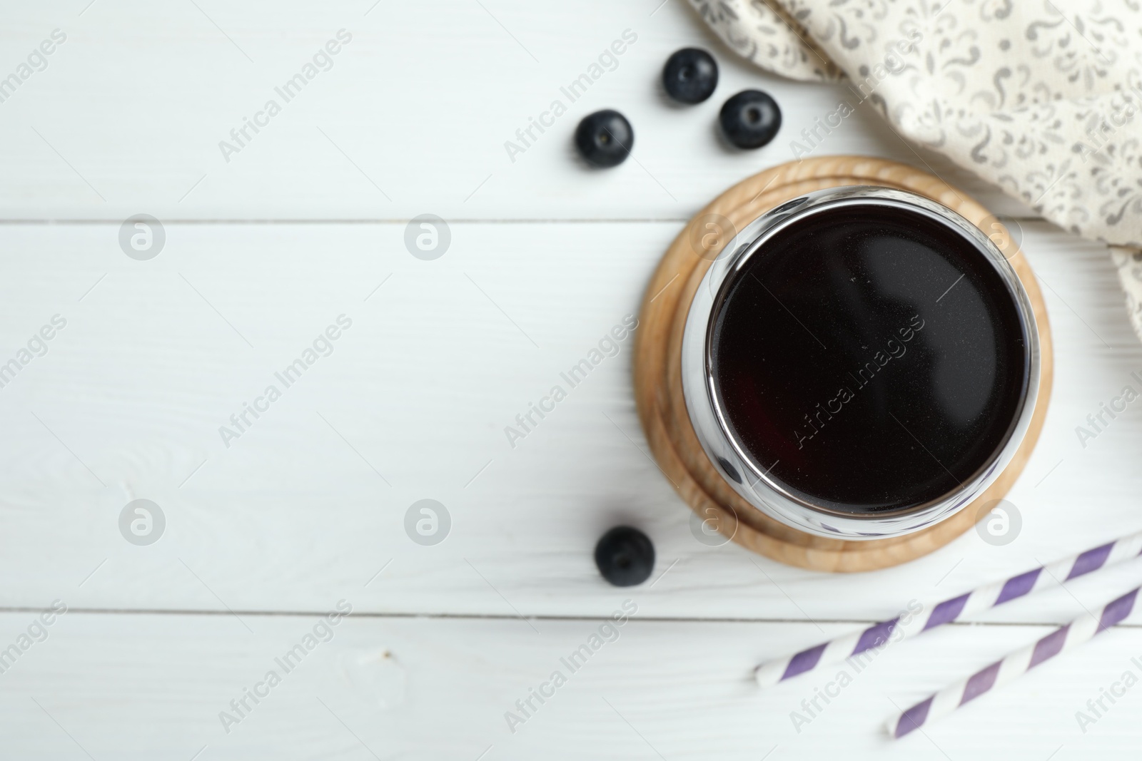 Photo of Tasty fresh acai juice in glass with berries on white wooden table, flat lay. Space for text