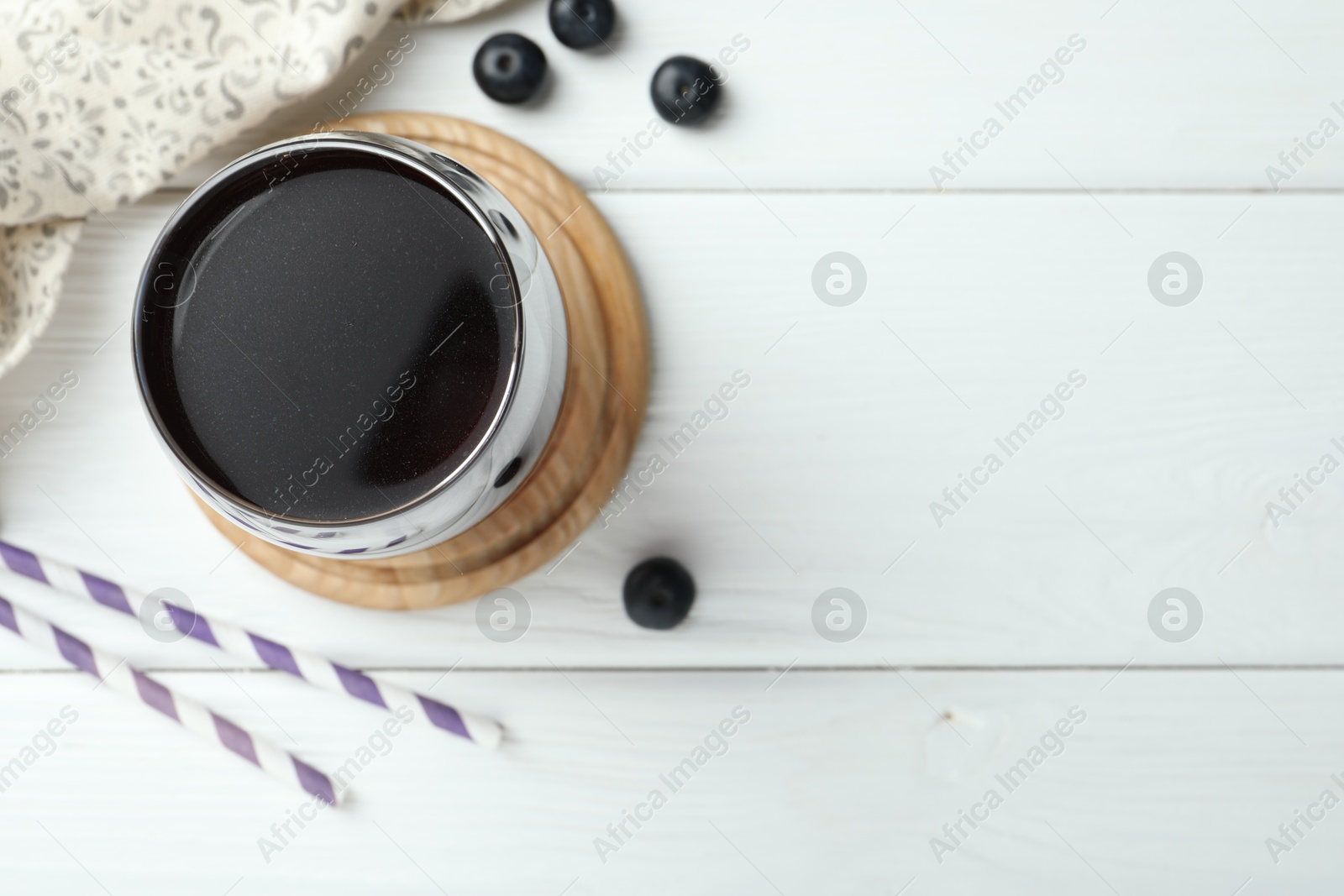 Photo of Tasty fresh acai juice in glass with berries on white wooden table, flat lay. Space for text