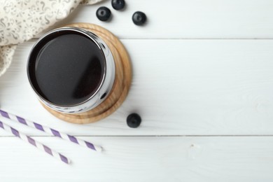 Photo of Tasty fresh acai juice in glass with berries on white wooden table, flat lay. Space for text