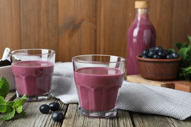 Tasty fresh acai juice in glasses with berries and mint on wooden table