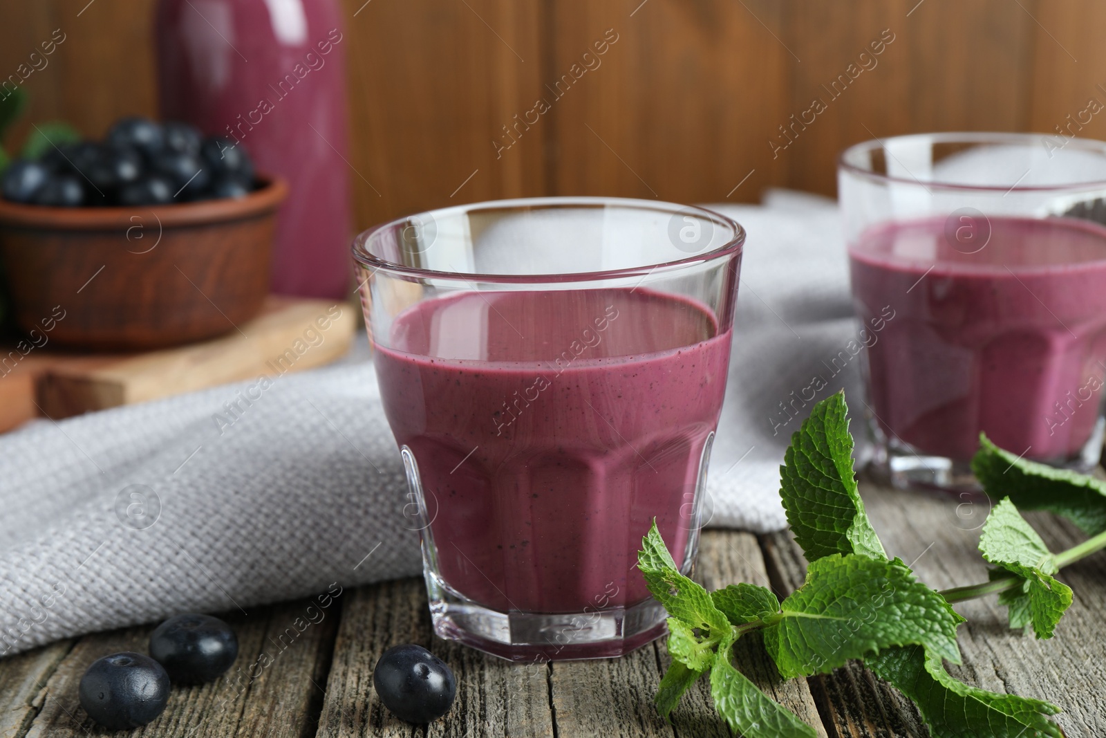 Photo of Tasty fresh acai juice in glasses with berries and mint on wooden table, closeup