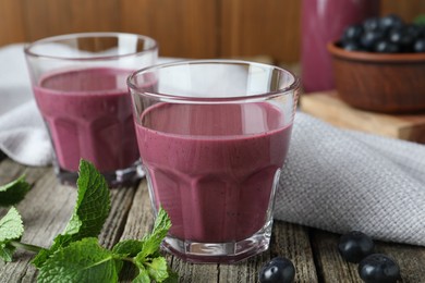 Photo of Tasty fresh acai juice in glasses with berries and mint on wooden table, closeup