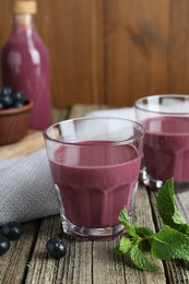 Photo of Tasty fresh acai juice in glasses with berries and mint on wooden table, closeup