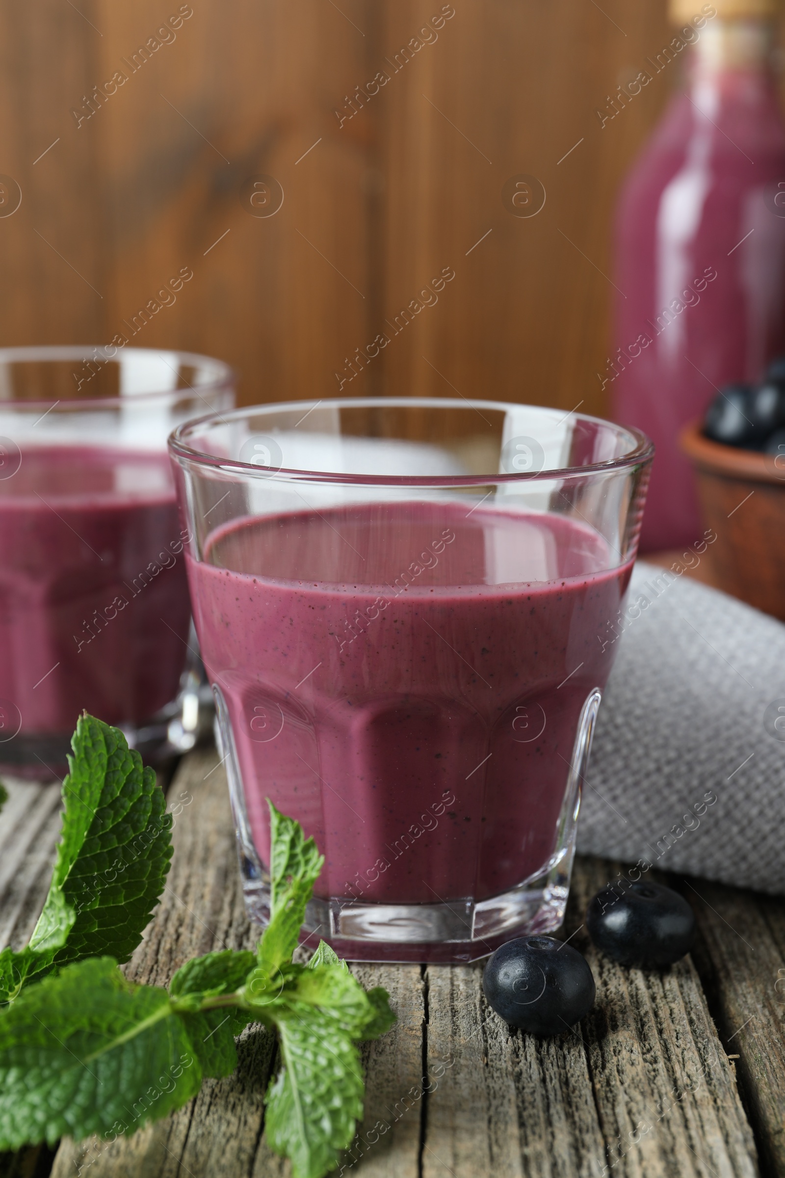 Photo of Tasty fresh acai juice in glasses with berries and mint on wooden table, closeup