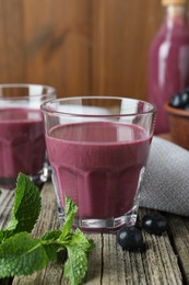 Tasty fresh acai juice in glasses with berries and mint on wooden table, closeup