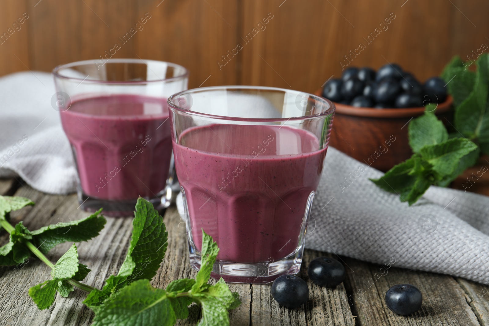 Photo of Tasty fresh acai juice in glasses with berries and mint on wooden table, closeup