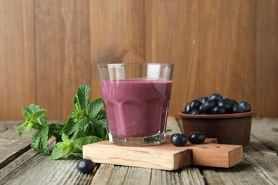 Tasty fresh acai juice in glass with berries and mint on wooden table