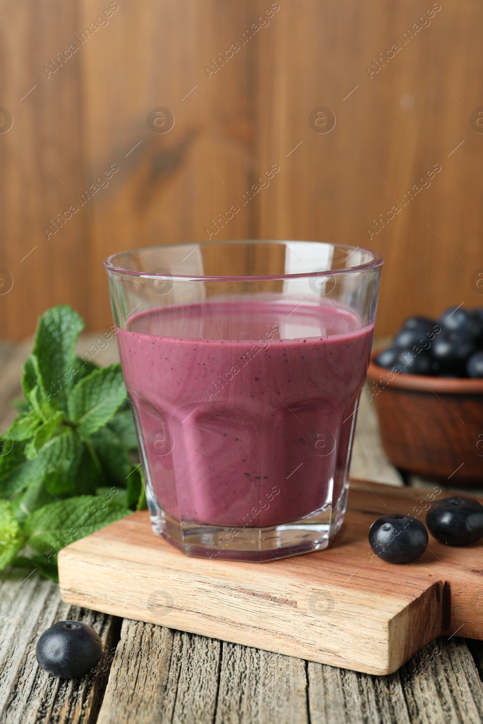 Photo of Tasty fresh acai juice in glass with berries and mint on wooden table