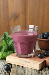 Photo of Tasty fresh acai juice in glass with berries and mint on wooden table