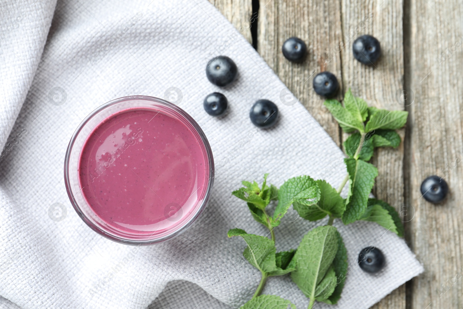 Photo of Tasty fresh acai juice in glass with berries and mint on wooden table, flat lay