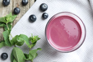 Photo of Tasty fresh acai juice in glass with berries and mint on table, flat lay