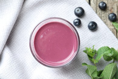 Photo of Tasty fresh acai juice in glass with berries and mint on table, flat lay