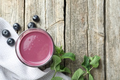 Photo of Tasty fresh acai juice in glass with berries and mint on wooden table, flat lay. Space for text