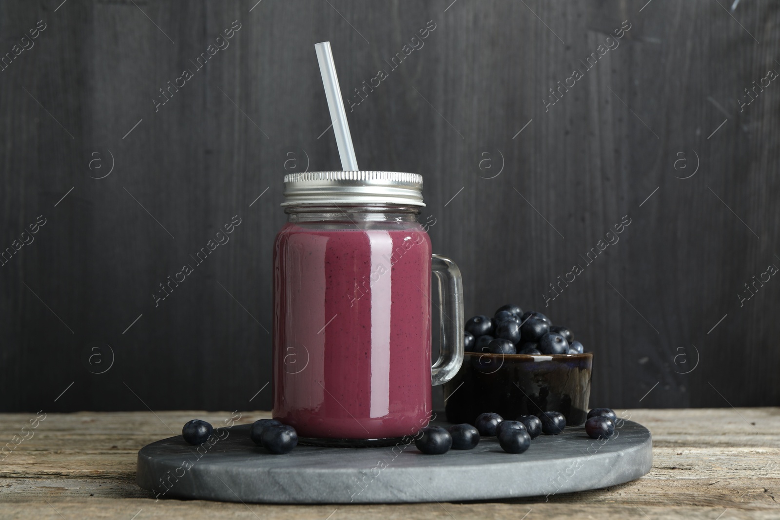 Photo of Tasty fresh acai juice in mason jar and berries on wooden table