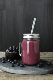 Photo of Tasty fresh acai juice in mason jar and berries on wooden table