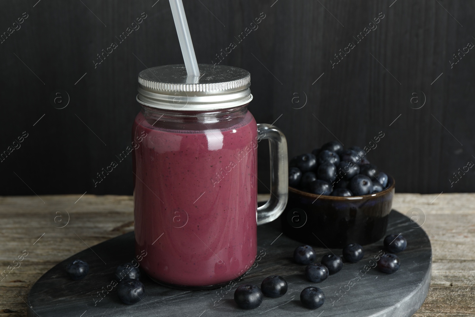 Photo of Tasty fresh acai juice in mason jar and berries on wooden table