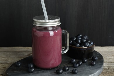 Tasty fresh acai juice in mason jar and berries on wooden table